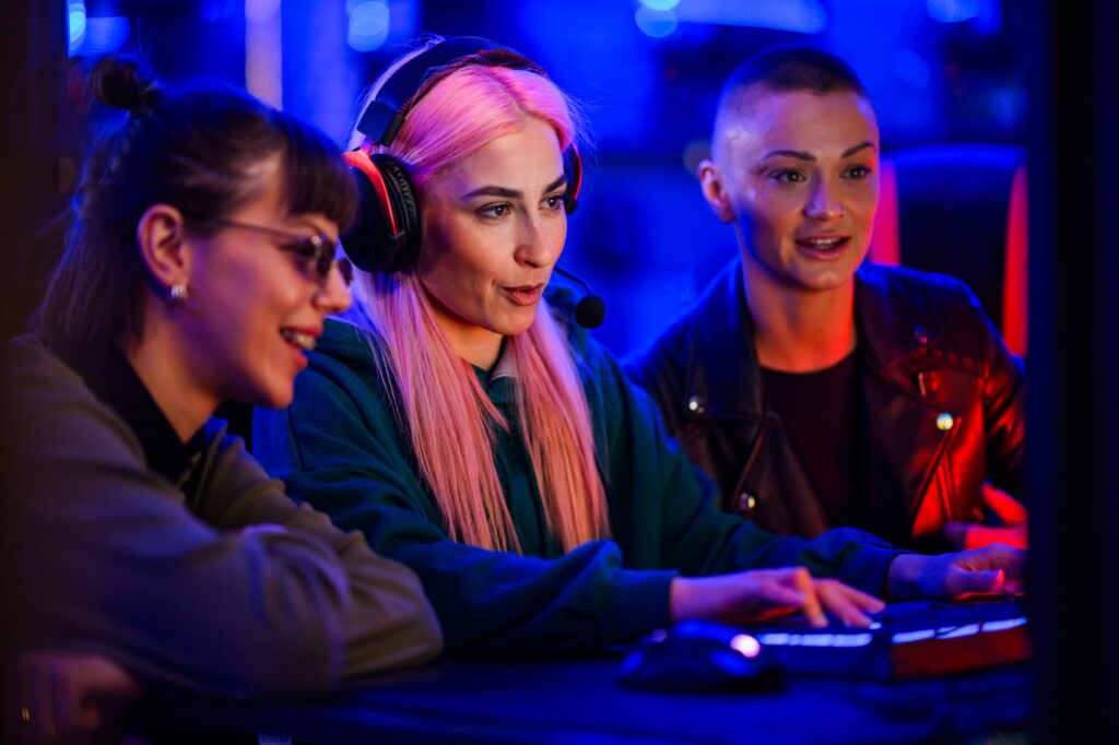 Woman gamer with pink hair sitting in a cyber club and playing a video game